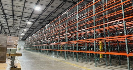 Tall selective pallet rack rows with orange beams in a 36-foot clear warehouse